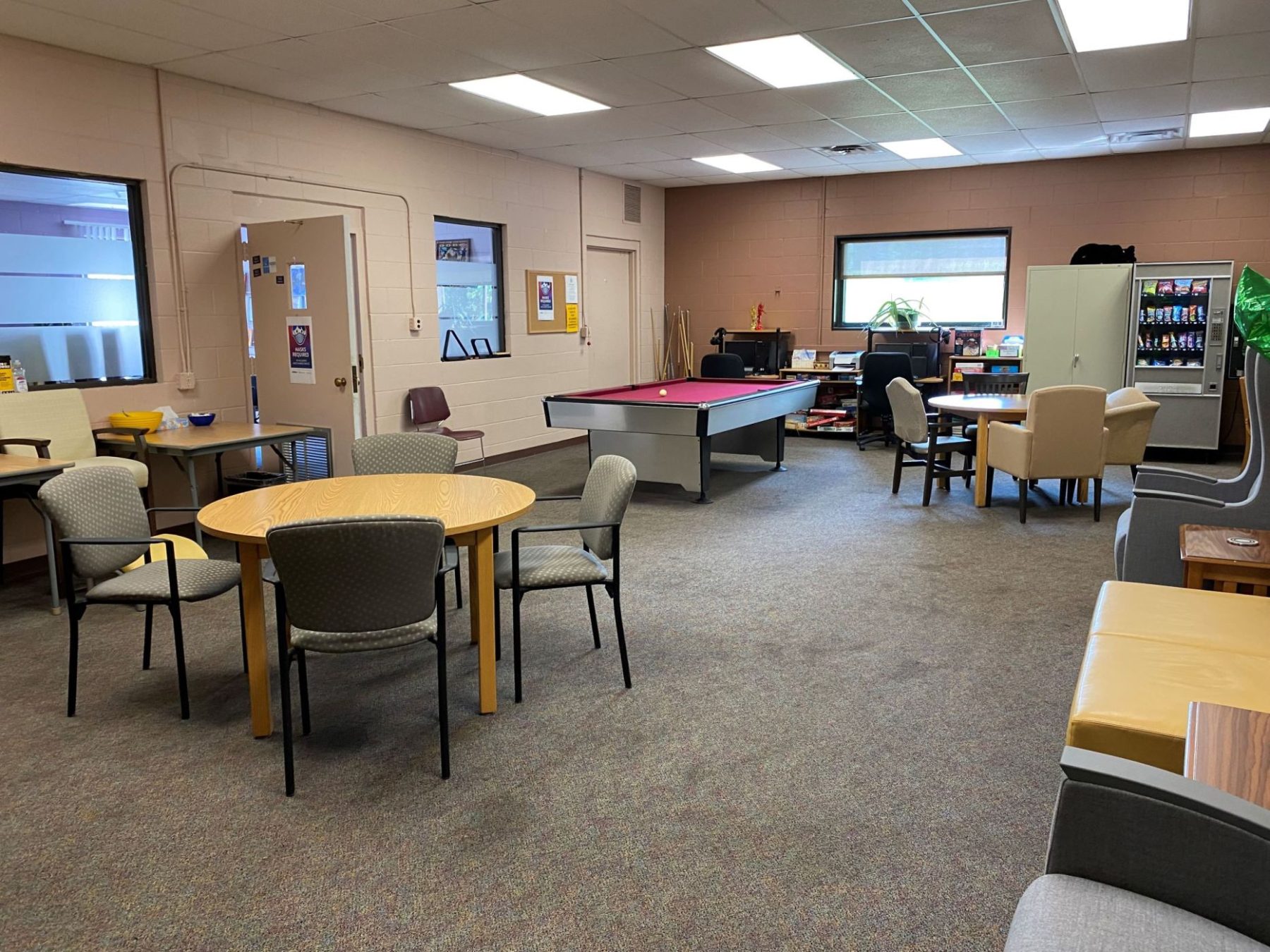 Big room with tables and chairs, a pool table, and computers.