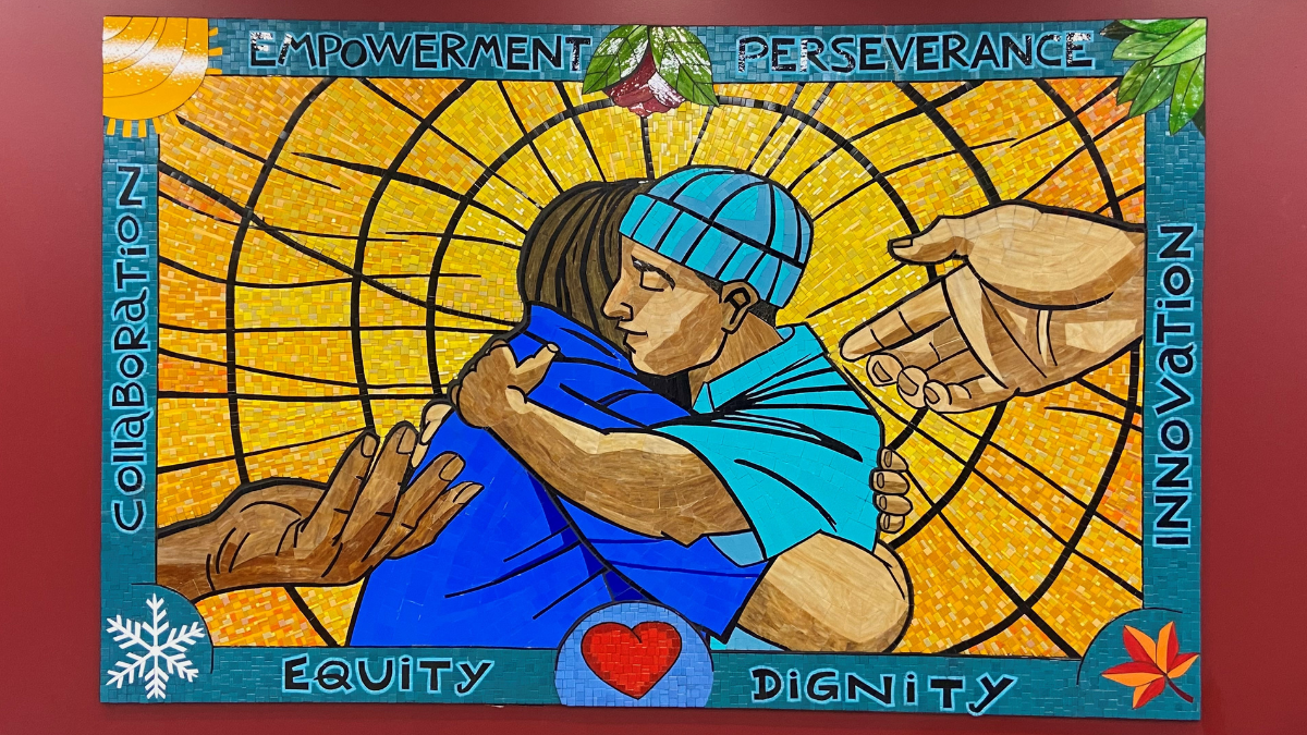 A mosaic artwork features two people hugging with the words empowerment, perseverance, dignity, collaboration, innovation, and